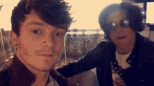 a man and a woman are posing for a picture together . the man is wearing headphones and sunglasses .