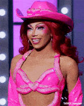 a woman with red hair is wearing a pink cowboy hat and a pink bra