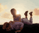 a woman is laying on a man 's lap with the sun behind them