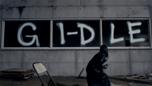 a person standing in front of a wall that says g1-dle