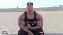 a man with a tattoo on his chest is sitting in front of a sign that says 5 % on it