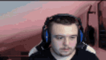 a man wearing headphones is sitting in front of a pink background .