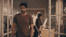 a man in a brown shirt is standing in front of a woman in a brown jacket .