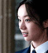 a close up of a woman 's face with a suit and tie