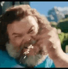 a man with a beard is making a funny face while eating a piece of food .