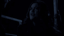 a woman is crying in the dark while holding a railing in a dark room .