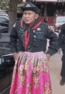 a man in a cowboy hat and pink skirt is standing in front of a car .