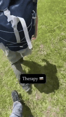 a person is walking in the grass with the word therapy on a black sticker