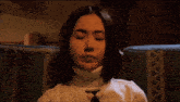 a woman with her eyes closed is wearing a sweater with a plaid pattern