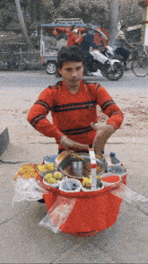 a man in a red sweater is standing in front of a cart full of food