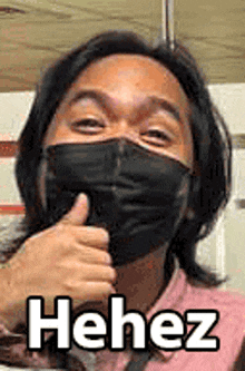 a man wearing a mask is giving a thumbs up sign .