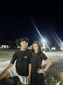 a man and a woman are posing for a picture and the man is wearing shorts with the number 77 on the side