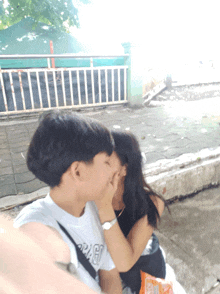 a man kissing a woman on the cheek while wearing a shirt that says ' a ' on the front