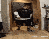 a man wearing a black shirt and shorts is dancing in a hallway