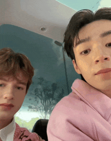 two young men are posing for a picture and one is wearing a pink hoodie