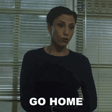 a woman standing in front of a window with the words go home written on her chest