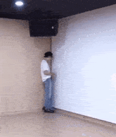 a man is leaning against a wall in a room with a white board .
