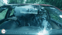 a man is driving a car with a zee5 logo on the dashboard