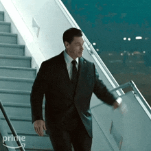 a man in a suit and tie is walking down a set of stairs with the word prime on the bottom right