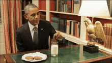 a man in a suit and tie is sitting at a desk with a plate of cookies and a glass of milk
