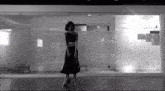 a black and white photo of a woman standing on a chair in a room