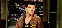 a man in a leather jacket is sitting in front of a window and says oh wow