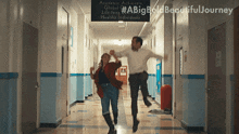 a man and a woman are jumping in the air in a hallway with a sign that says academic achiever
