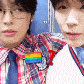 a man wearing a plaid shirt has a rainbow pin on his chest