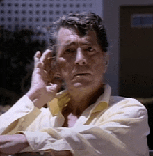 a man in a yellow shirt has his hand on his face