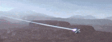 a jet is flying over a desert with mountains in the background and a laser beam coming out of it .