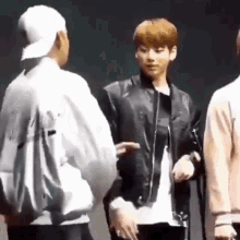 a group of young men are standing next to each other on a stage talking to each other .