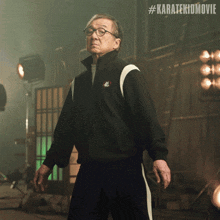 a man in a black jacket stands in front of a sign that says karatekidmovie