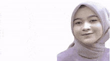 a woman wearing a hijab is smiling in front of a sign that says " alhamdulillah "
