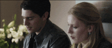 a man and a woman are sitting next to each other looking at something