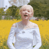 a woman is standing in a field of yellow flowers .