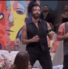 a man in a black vest is dancing in front of a group of people .
