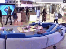 a group of people are gathered in a living room with a couch and tables