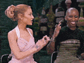 a woman in a pink dress talks to another woman