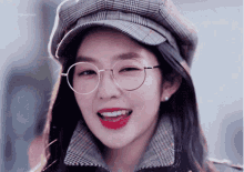 a girl wearing glasses and a hat is smiling