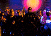 a group of people are dancing in front of a large pink light