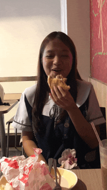 a girl eating a chicken sandwich with a straw in her mouth