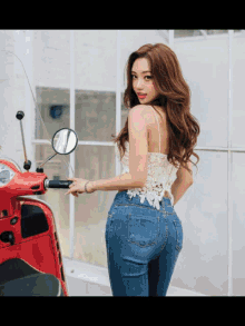 a woman standing next to a red scooter with a mirror on it