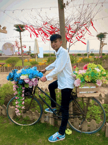 a boy sits on a bicycle with a basket full of flowers