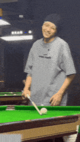 a man is playing pool and smiling while holding a cue