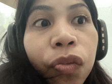 a woman wearing headphones making a face with her eyes closed