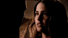 a close up of a woman 's face looking at a man in a dark room .