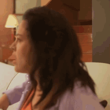 a woman is sitting on a couch in a room with stairs in the background .