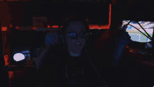 a person wearing headphones and sunglasses is sitting in front of a microphone in a dark room