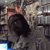 a man with long hair and glasses is sitting in front of a computer with hearts around him