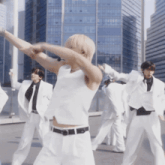 a group of young men in white suits are dancing in front of a skyscraper
